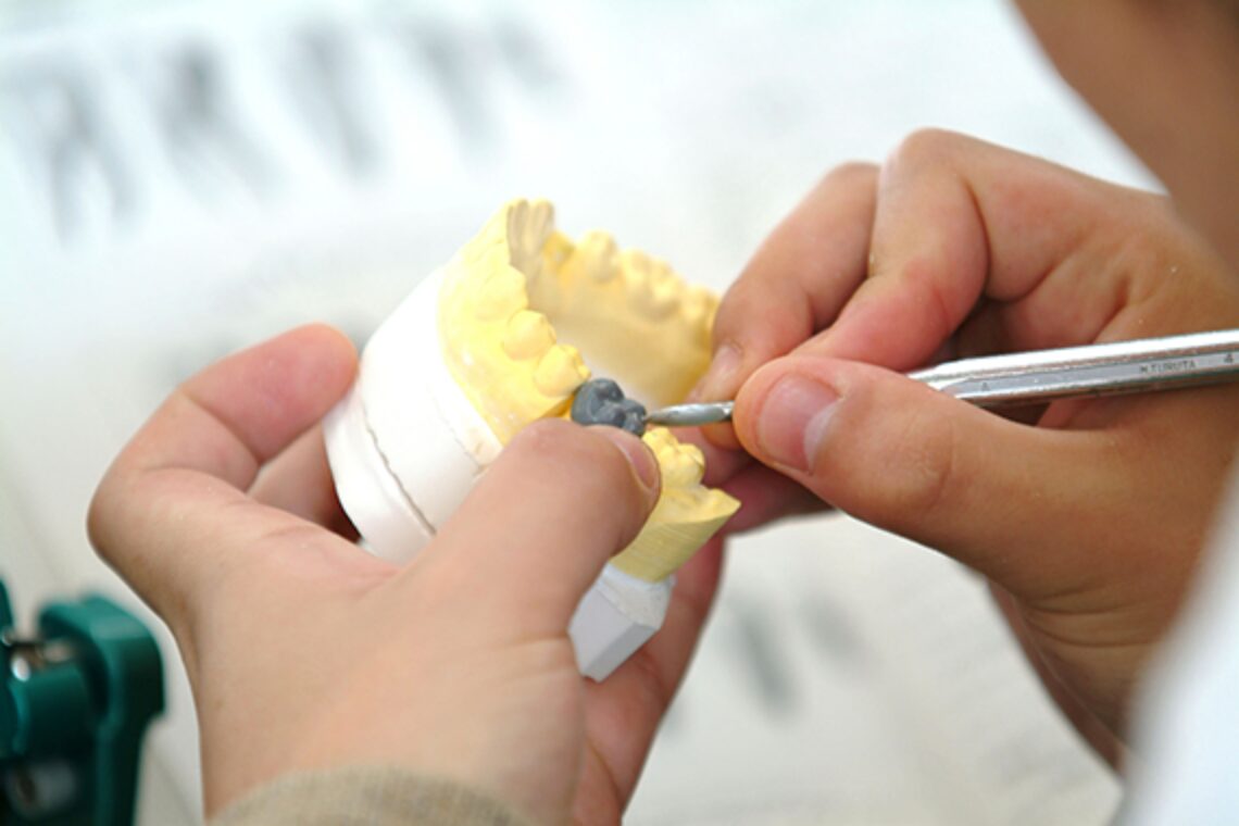 歯科医師が子供用の歯型模型を用いてマウスガード製作の調整をしている様子